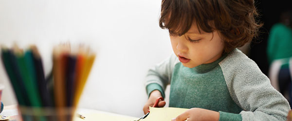 child doing a craft - cutting paper with scissors